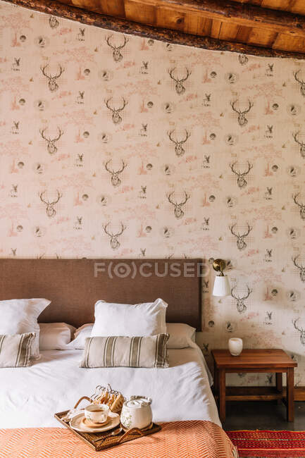 Intérieur de la chambre élégante avec lit confortable recouvert de couvercle près de la fenêtre décorée de rideaux — Photo de stock