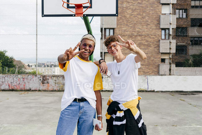Dos chicos adolescentes de pie y saludando en la cancha urbana - foto de stock