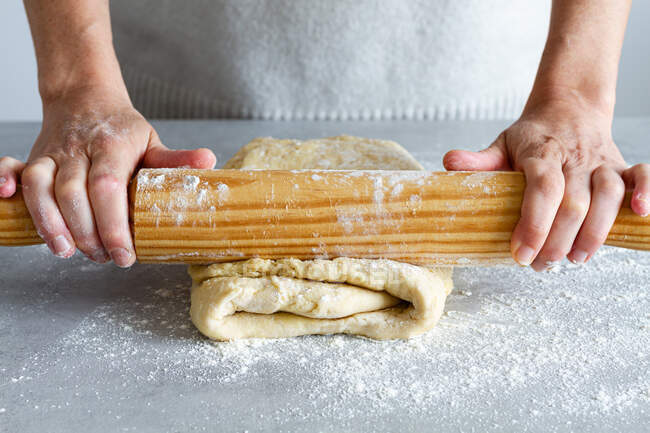 Кукурудза невизначена жінка-кухарка, що розкачує м'яке тісто, використовуючи дерев'яний штифт з борошном під час приготування їжі в будинку — стокове фото