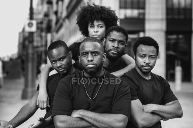Black and white of young self assured African American partners with crossed arms looking at camera in town — Stock Photo