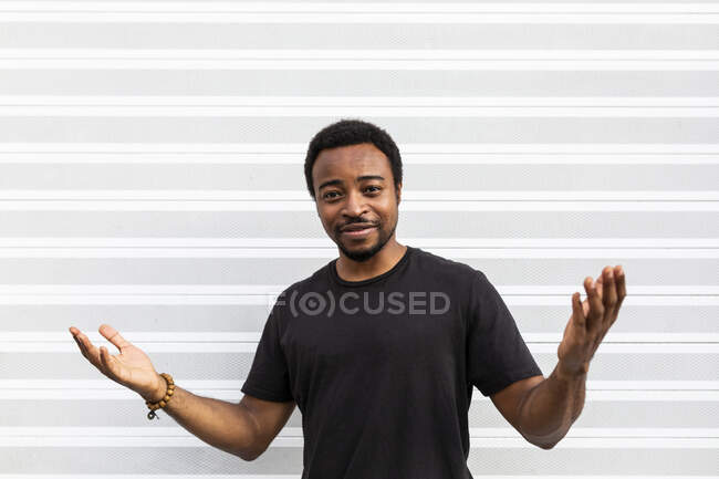 Contenu homme afro-américain en t-shirt noir debout regardant la caméra sur fond clair — Photo de stock