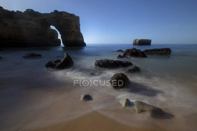 Vista pitoresca de formações rochosas arqueadas na costa oceânica sob céu azul na Praia da Abandeira, Algarve Portugal — Fotografia de Stock