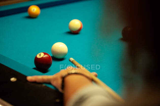 Сосредоточенный бородатый мужчина бьет по мячу кием во время игры в бильярдном бассейне — стоковое фото