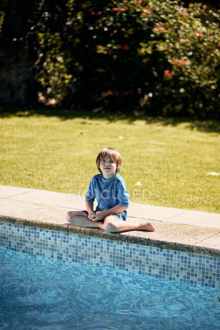 Adorable petit garçon se reposant avant de nager dans la piscine extérieure — Photo de stock