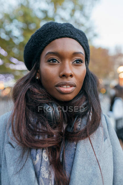 Gros plan Femme afro-américaine debout dans la rue des vêtements de dessus et avec écouteurs — Photo de stock