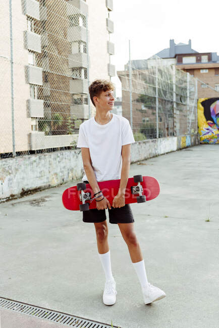 Schöner kaukasischer Teenager mit Skateboard posiert auf der Straße — Stockfoto