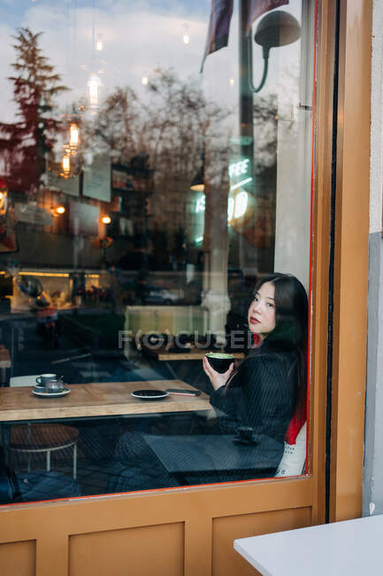 Длинноволосая брюнетка азиатка пьет кофе о, кофейня — стоковое фото
