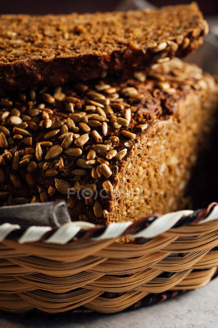 Nahaufnahme von leckerem geschnittenem Brot mit brauner Kruste und knusprigen Sonnenblumenkernen oben im Weidenkorb — Stockfoto