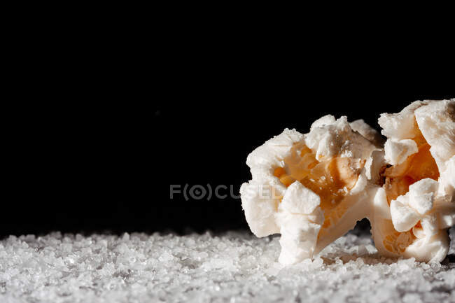 Primo piano di un delizioso popcorn su uno strato di sale — Foto stock