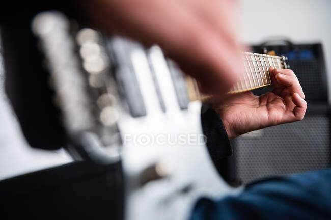 Low angle side view of concentrated blind guitarist playing music instrument while rehearsing melody at home — Stock Photo