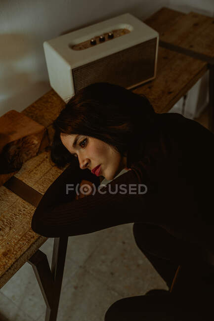 Ângulo alto de mulher sonhadora inclinada na mesa na sala retro e olhando para longe — Fotografia de Stock