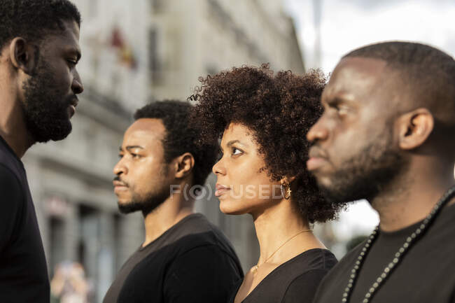 Crop bearded African American male social justice warriors with female partner in black wear in town — Stock Photo