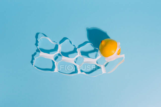 From above bright whole ripe and juicy lemons between thin plastic pack rings with holes — Stock Photo