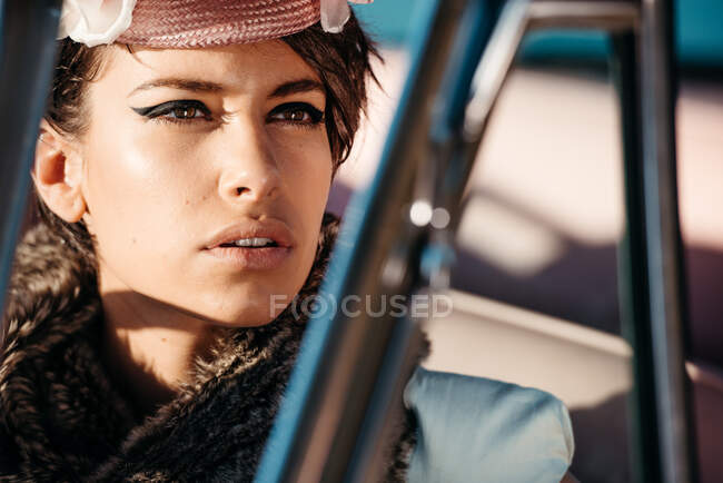 Colheita fêmea na moda com flor no chapéu no automóvel enquanto olha para longe — Fotografia de Stock