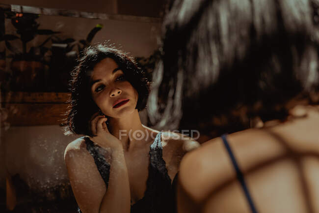 Donna pacifica seduta a guardarsi in specchio rettangolare sul pavimento in camera — Foto stock