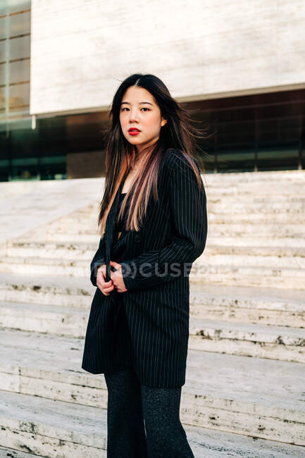 Lunghi capelli bruna donna asiatica in piedi sulle scale e guardando la fotocamera — Foto stock