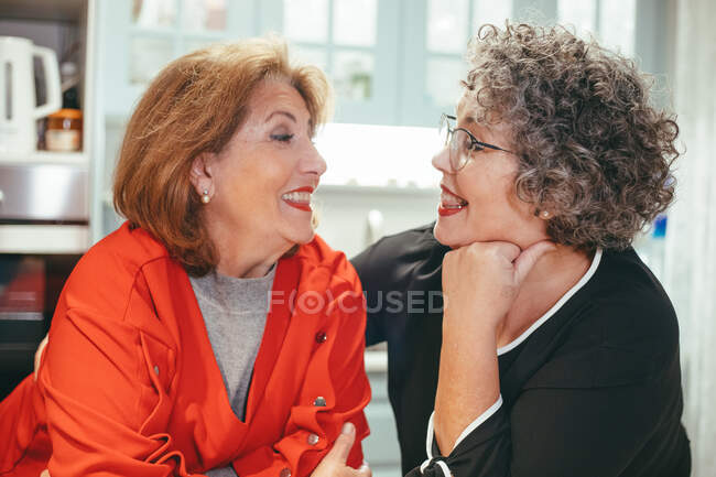 Feliz meia idade lésbicas mulher com sorrindo fêmea amado olhando para o outro no casa — Fotografia de Stock
