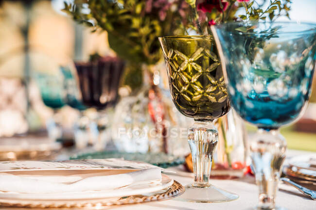 Крупним планом подається святковий стіл з кришталевими келихами столярна серветка на тарілці біля букету свіжих квітів на весілля — стокове фото