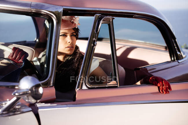 Ritaglio femminile alla moda con fiore sul cappello e guanti in pelle toccando volante in automobile, mentre guardando altrove — Foto stock