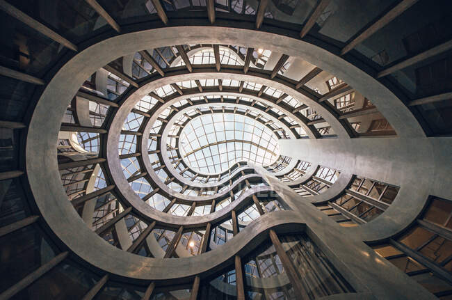 Bajo ángulo de diseño creativo del edificio contemporáneo de varios pisos con paredes onduladas en la ciudad a la luz del día - foto de stock