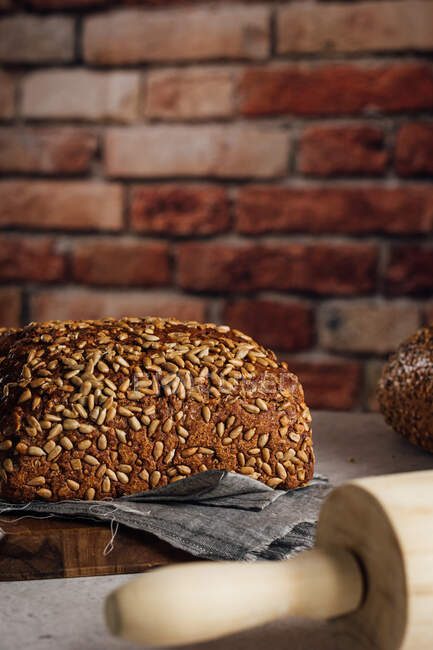 Delicious wholegrain bread on cutting board on table — Stock Photo
