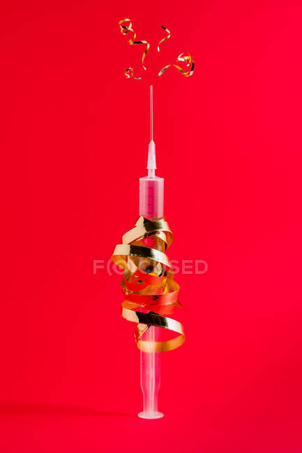 Plastic injector with curved golden ribbon and pointed needle representing firework concept during festive event — Stock Photo