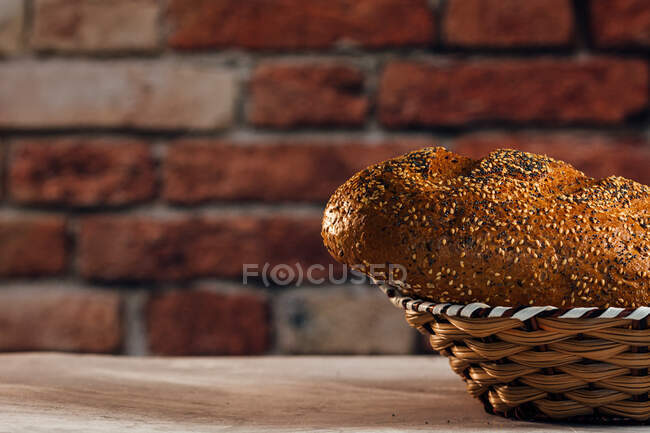 Боковой вид на вкусный нарезанный хлеб с коричневой корочкой и хрустящие семечки подсолнечника сверху в плетеной корзине — стоковое фото