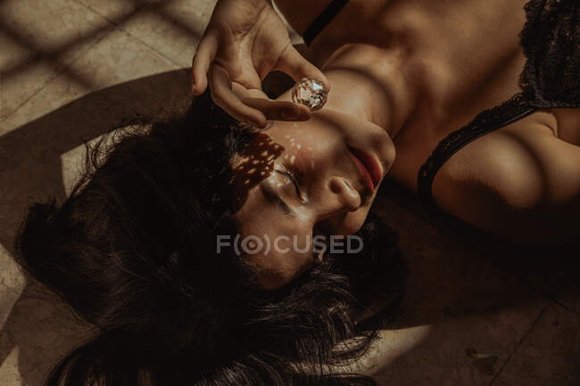 From above of tender female lying with glass crystal ball reflecting sunlight in room — Stock Photo