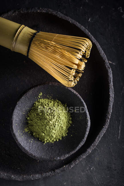 Сверху сушеные чайные листья в куче на тарелке с chasen для чайной церемонии — стоковое фото