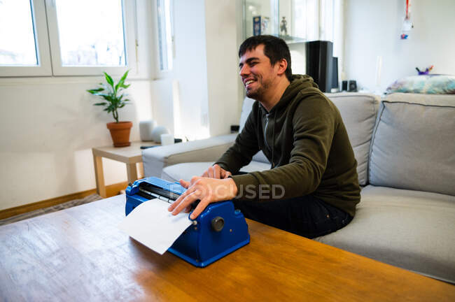 Мужчина со слабым зрением печатает на машинке с тактильной системой письма дома — стоковое фото