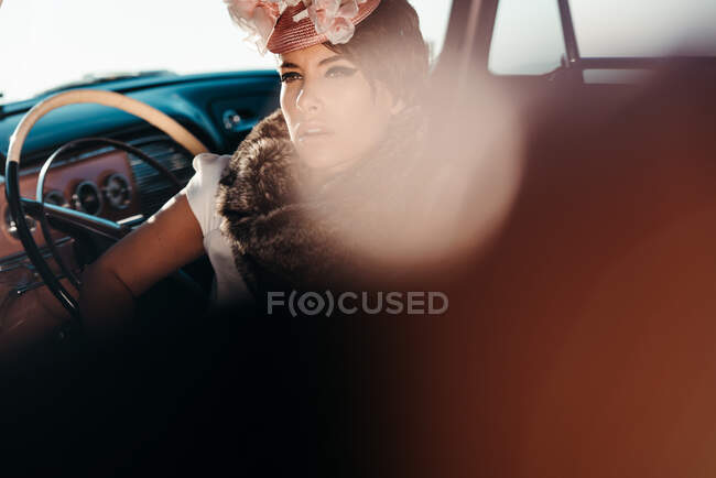 Урожайная трезвенница с цветочком на шляпе в машине, отводя взгляд — стоковое фото