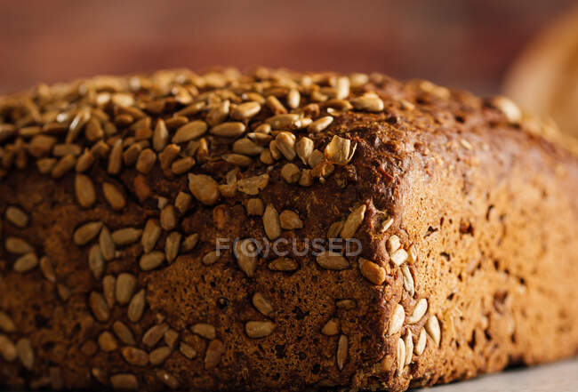 Вкусный цельнозерновой хлеб на доске на столе — стоковое фото