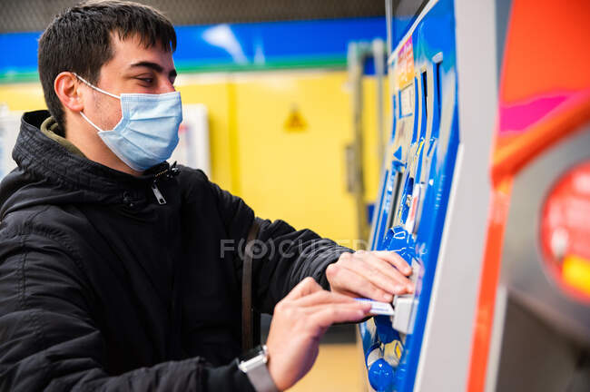 Vista lateral del hombre ciego en máscara médica pagando el billete en terminal en metro - foto de stock