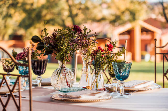 Primo piano del tavolo festivo servito con bicchieri di cristallo posate tovagliolo sul piatto vicino mazzo di fiori freschi per matrimonio e scheda menu — Foto stock