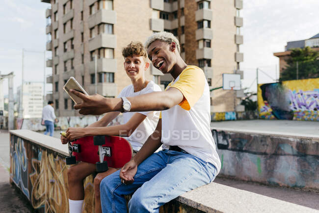 Deux beaux adolescents avec skateboard prenant selfie dans la rue — Photo de stock