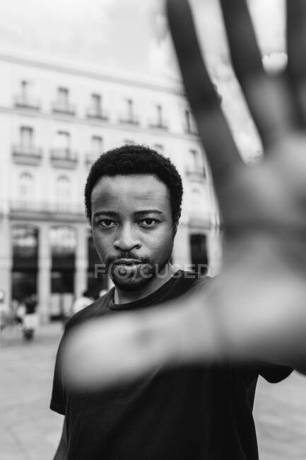 Чорно-білий молодий спокійний етнічний чоловік показує стоп жест, дивлячись на камеру в місті — стокове фото