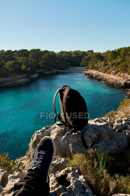 Belle vue sur la plage, baie d'eau de mer bleu turquoise, avec un ciel dégagé, assis sur une falaise regardant les pieds, île de Majorque Espagne., — Photo de stock