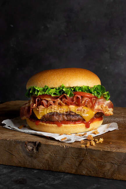 Dettaglio di un delizioso hamburger con formaggio e pancetta sul tavolo di legno — Foto stock