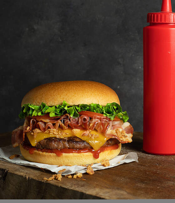 Détail d'un délicieux hamburger au fromage et bacon sur la table en bois — Photo de stock