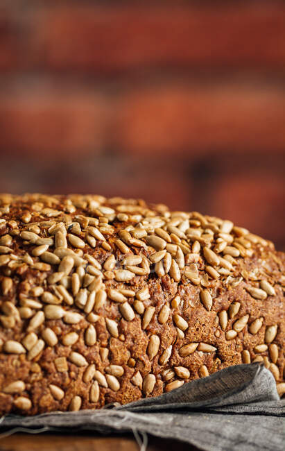 Délicieux pain complet sur planche à découper sur table — Photo de stock