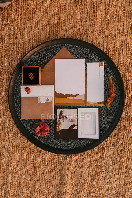 Top view of white greeting cards placed on black round tray with bright plants on wicker surface during wedding celebration — Stock Photo