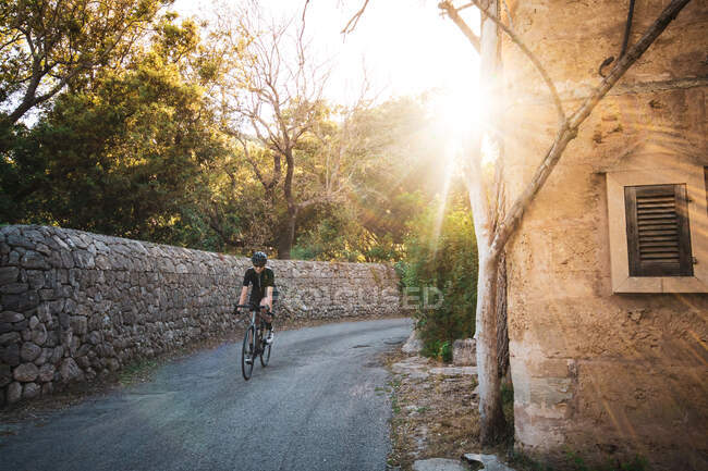 Anonimo ciclista donna in abbigliamento casual in bicicletta da sola in strada vuota sulla natura — Foto stock