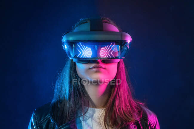 Unrecognizable female wearing modern headset while exploring virtual reality in dark room — Stock Photo