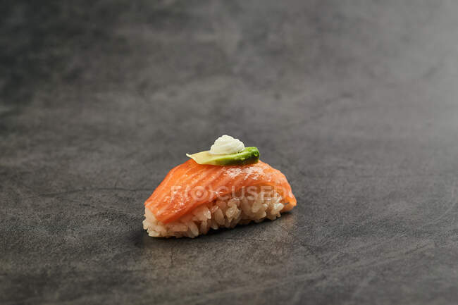 Высокий угол вкусовых суши нигири с ломтиком лосося на рисе, увенчанном тонким ломтиком авокадо и сливочным сыром — стоковое фото
