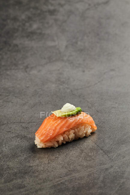 Alto ángulo de sushi nigiri sabroso con rebanada de salmón sobre arroz cubierto con rebanada delgada de aguacate y queso crema - foto de stock