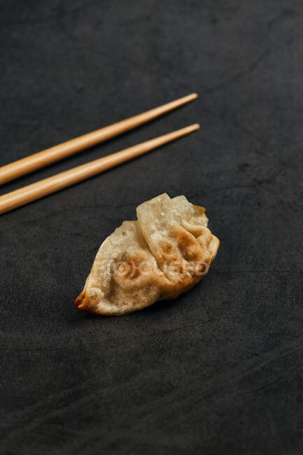 Високий кут смаженої гіози традиційної східної їжі з бамбуковими паличками на сірому столі. — стокове фото