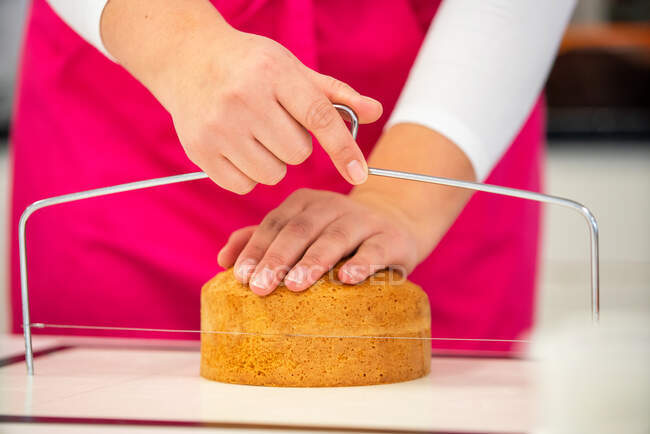 Ernte unkenntlich weiblich mit professionellen Geräten Schneiden frisch gebackener Kuchen auf Teile in Bäckerei — Stockfoto