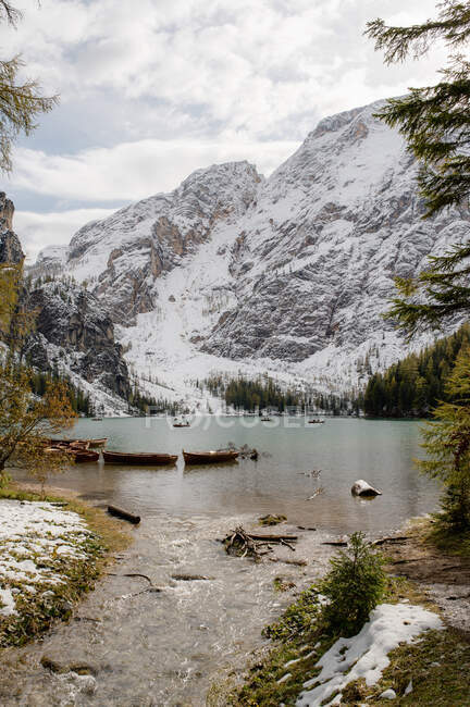 Picturesque scenery of Lago di Braies lake surrounded by evergreen woods and mountains covered with snow — Stock Photo