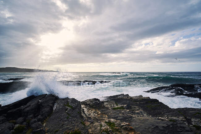 Cenário pitoresco de litoral íngreme rochoso coberto com lavagem de grama por ondas salpicantes — Fotografia de Stock