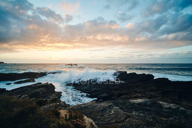 Paesaggio pittoresco di costa rocciosa scoscesa coperta di erba lavata da onde spruzzanti — Foto stock